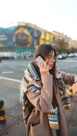 una mujer joven hablando por teléfono en la ciudad.