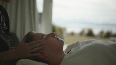 senseful hands holding young caucasian woman's head during head massage