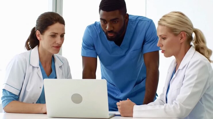 Team medico eterogeneo di medici e infermieri che collaborano attorno a un computer portatile