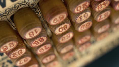 cinematic close-up smooth dreamy backwards shot from above of bingo wooden barrels in a row, woody figures, old numbers background, vintage board game, 4k commercial rotating gimbal video