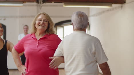 medium shot of senior couple rehearsing dance with teacher