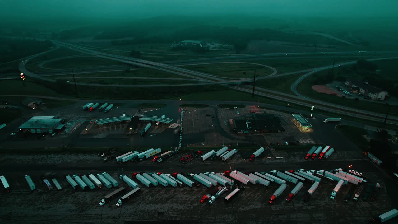 Night time truck stop aerial of Petro TA Travel Center. Moody hazy scene. Patterns of parked semi trucks.