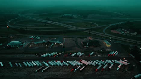 night time truck stop aerial of petro ta travel center. moody hazy scene. patterns of parked semi trucks.