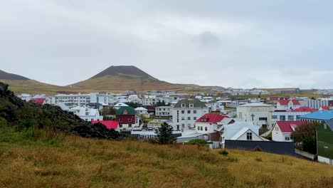 the town of vestmannaeyjabær with helgafell volcano in background on cloudy day