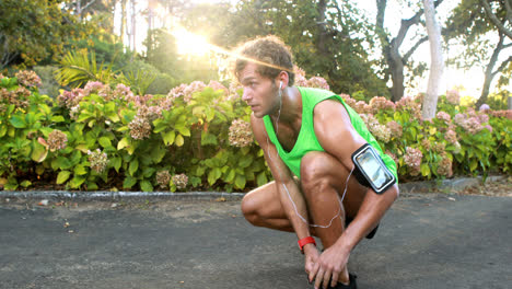 Man-tying-his-shoe-laces-while-jogging-in-park