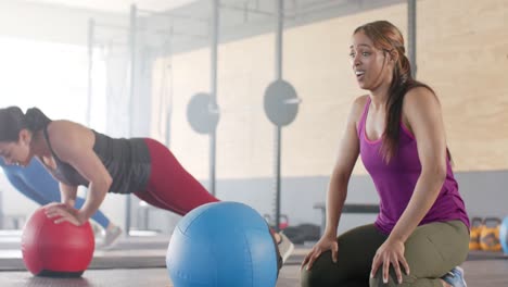 Mujer-Birracial-Cansada-E-Inalterada-Después-De-Hacer-Ejercicio-Con-Balón-Medicinal-En-Clase-De-Fitness,-Cámara-Lenta