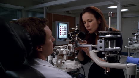 woman conducts eye exam on man using medical equipment