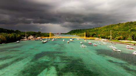 Barcos-En-El-Mar-De-Bali-Con-Un-Puente-Amarillo-Que-Conecta-Nusa-Lembongan-Y-La-Isla-Ceningan-Durante-Una-Tormenta-En-Indonesia