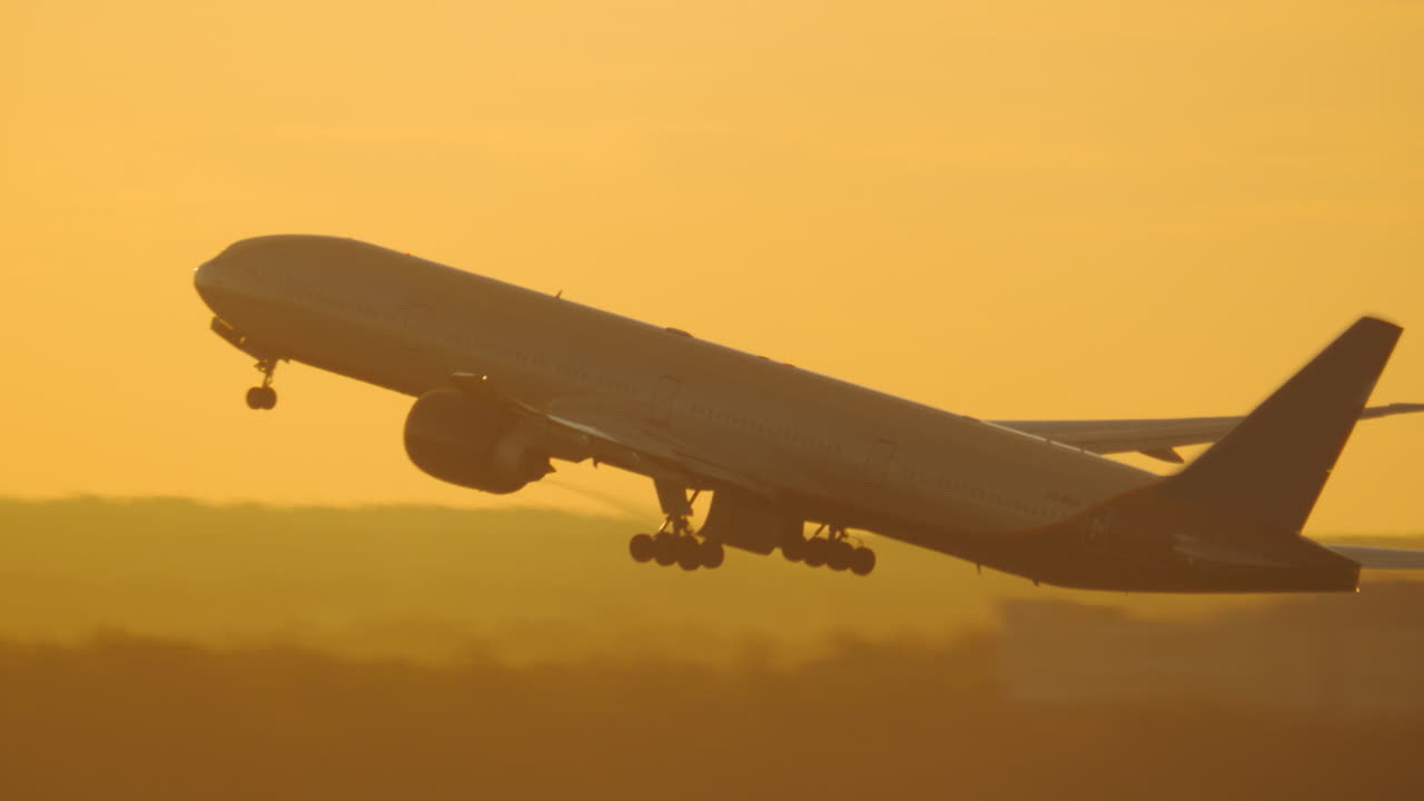 Aircraft taking off and ascending against golden sunset sky