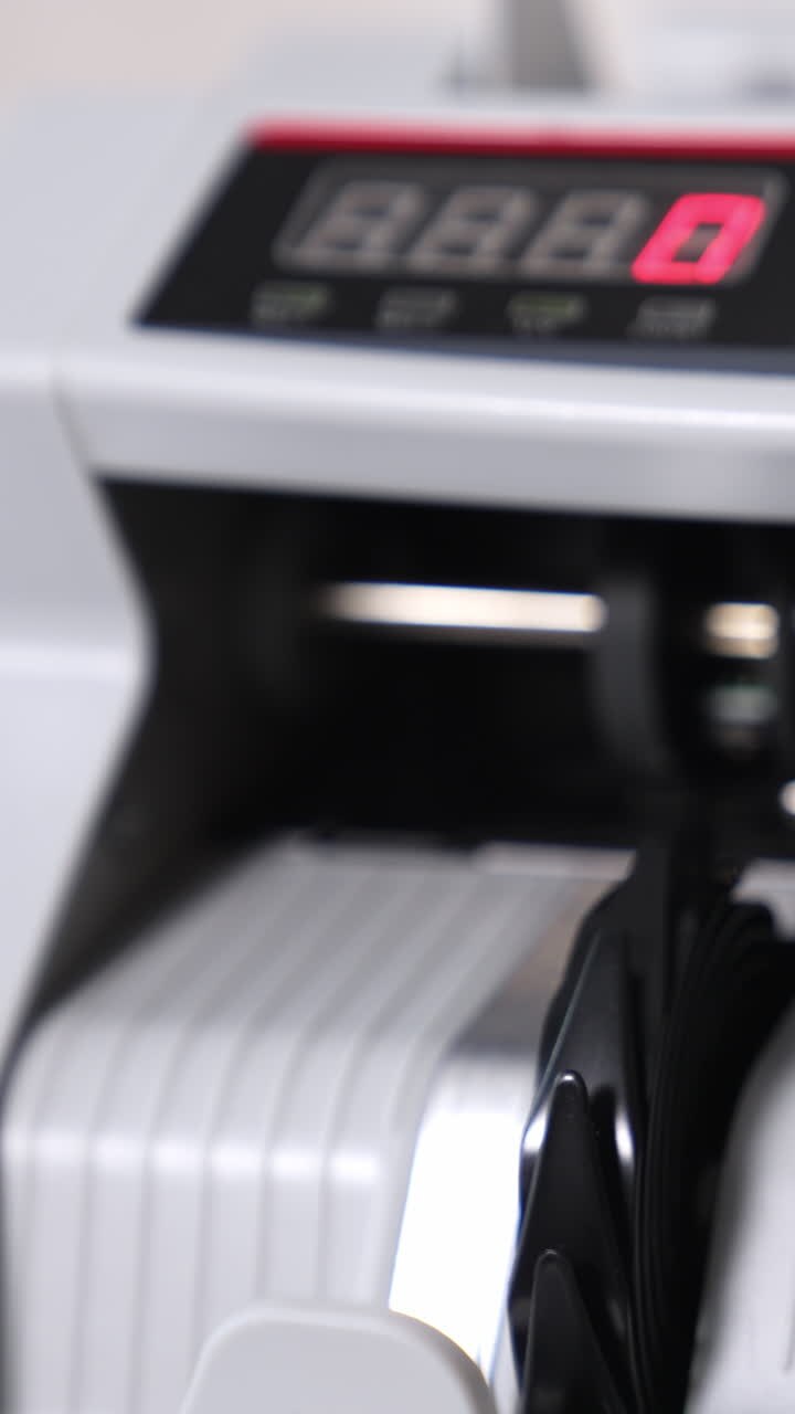 Wad of hundred dollar bills being counted in the banking equipment. Money rotated in machine and then stop. Close up. Vertical video