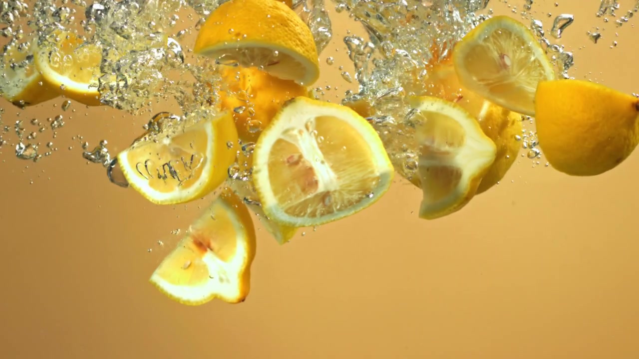 Fresh Sliced Lemons Falling into Water with Bubbles
