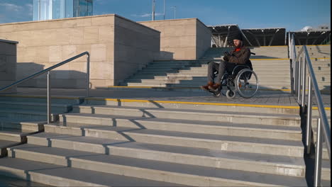 man in wheelchair using smartphone on steps