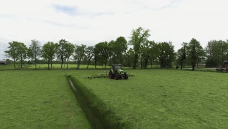 tractor driving on dutch grass farmland, drone moving around subject