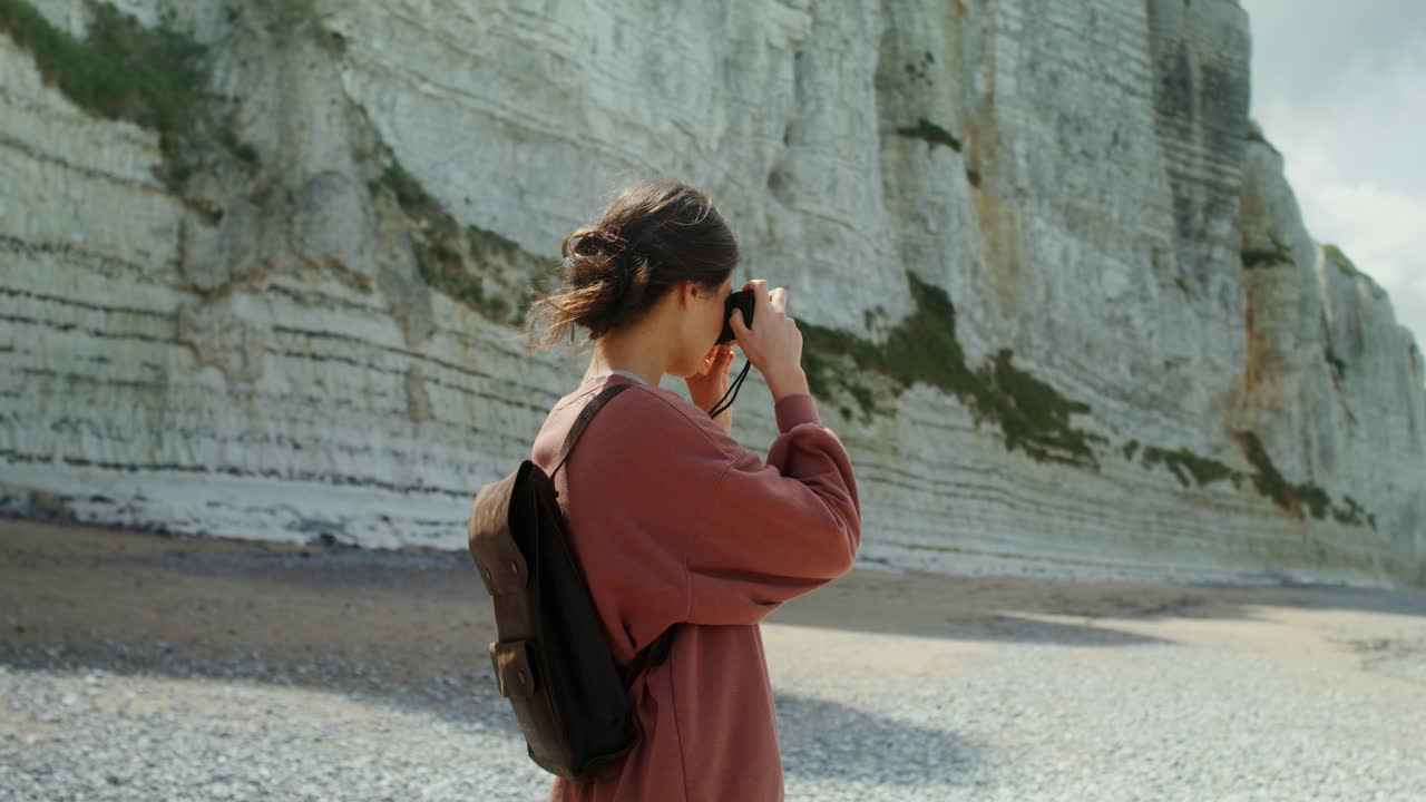mujer tomando fotos en una playa por los acantilados blancos de dover