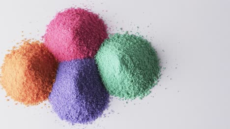 video of close up of heaps of multi coloured sand grains and copy space on white background