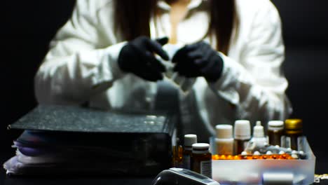 el médico con guantes negros cierra el archivo y toma la ampolla y el termómetro
