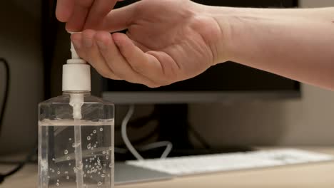 a pair of caucasian hands pressing down on a hand sanitizer bottle dispensing a measure of liquid onto the hands as the hands then apply it in slow motion