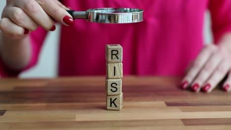 magnifying glass examining 'risk' blocks on table