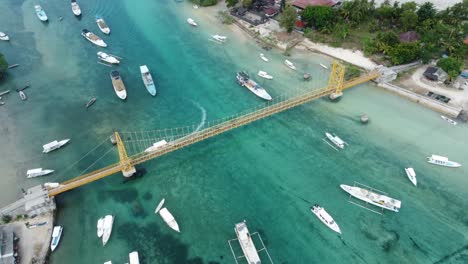 aerial 4k drone footage: scooters crossing the iconic and picturesque yellow bridge connecting nusa lembongan and nusa ceningan islands in bali