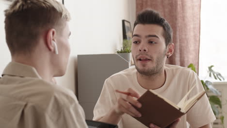 two young men sitting at table and communicating