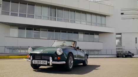 classic convertible car in front of modern building