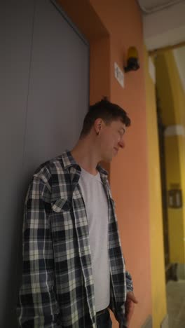 man in plaid shirt leaning against a wall