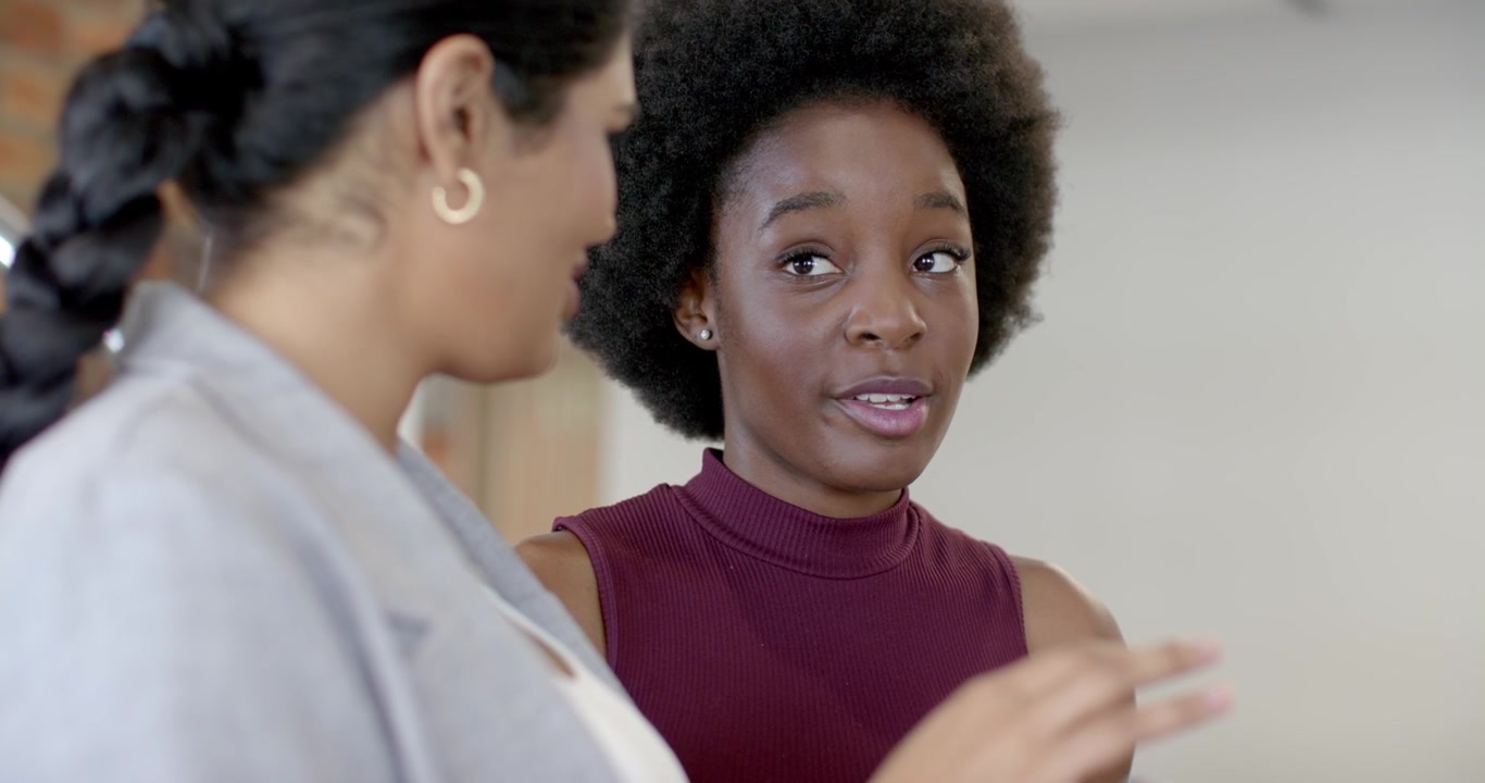 Diverse female team in blazer maroon top after pointing swiping tablet with watch working at office