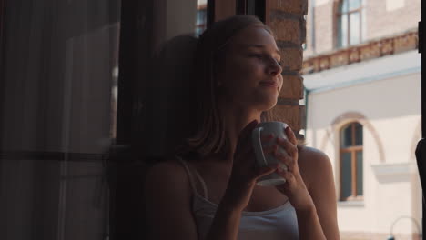 woman enjoying a drink at a window