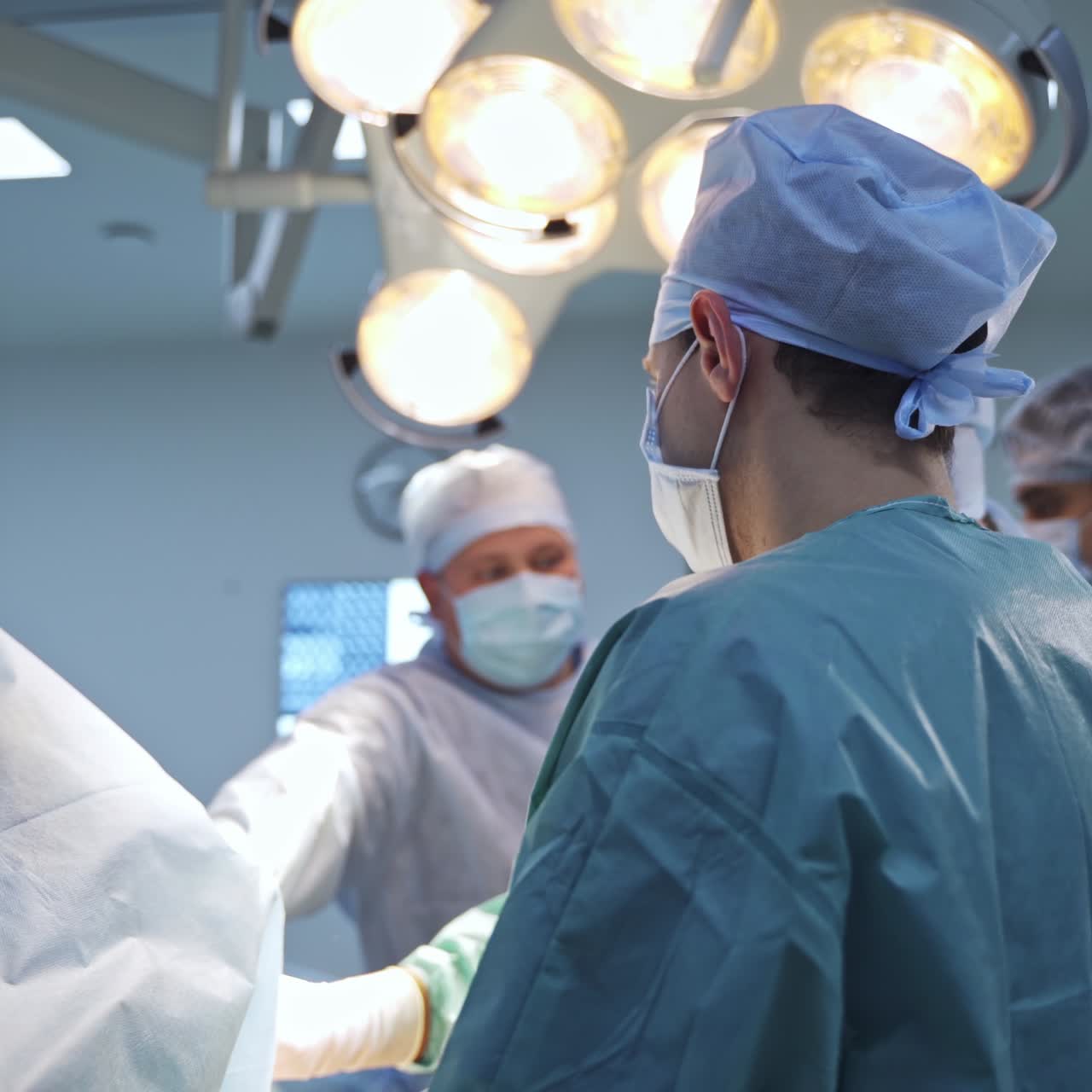 Spine trauma operation performed by a big group of surgeons. Doctors use metal tools and discuss the process together. Blurred backdrop