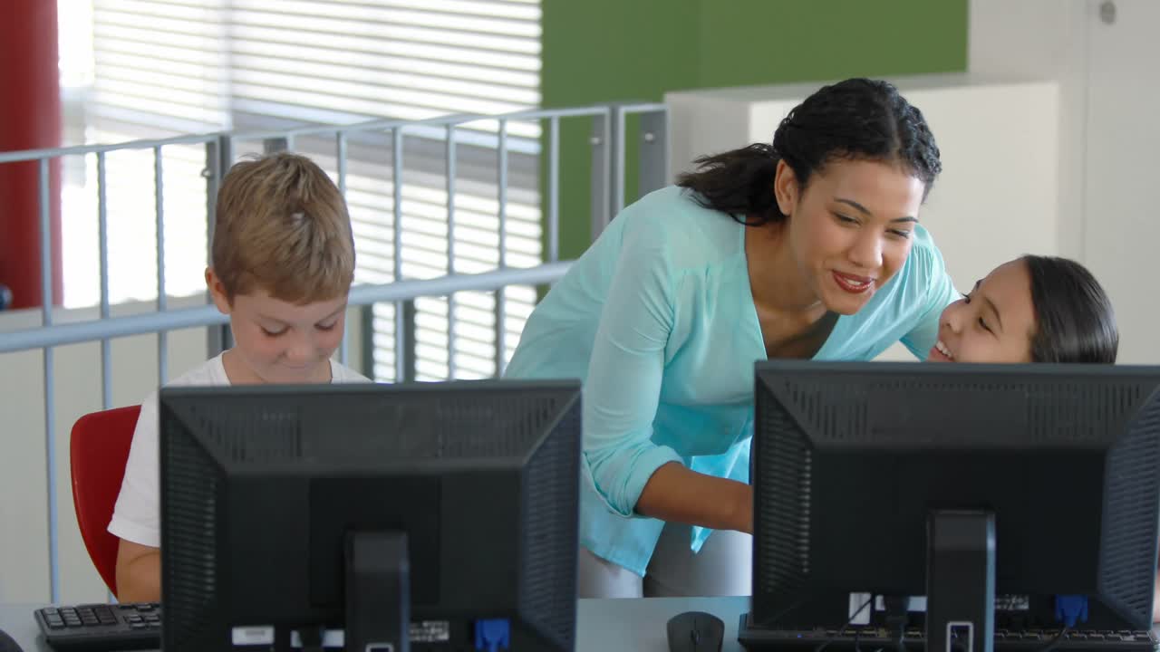 Teacher assisting schoolgirls in learning computer