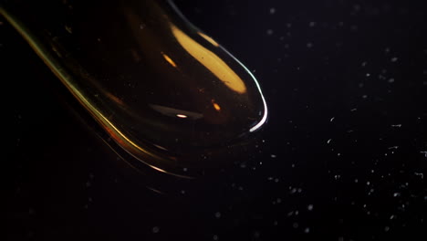 oil drop flowing on black background, viscosity concept, extreme closeup