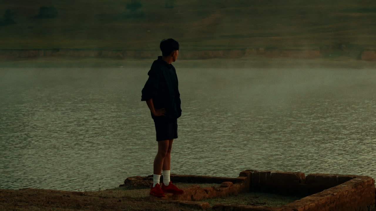 Man standing by a lake in the morning mist