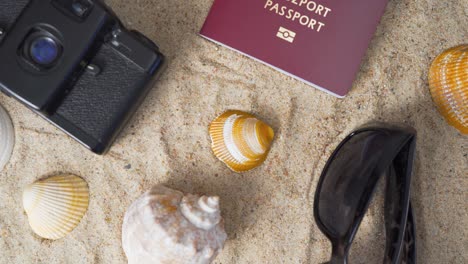 passport, vintage film camera, sunglasses and seashells on golden beach sand. summer travel abstract concept. rack focus shot.