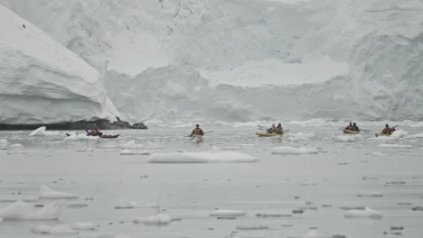 kayakers in front of close glacier and mountains along shore