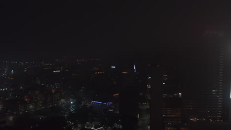 Aerial-Low-light-scene.-Forwards-ascending-fly-above-night-downtown.-Sparsely-lit-tall-buildings.-Dallas,-Texas,-US