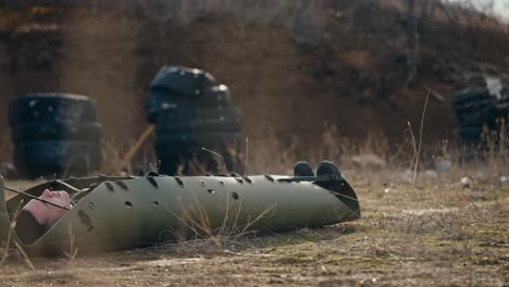 Close-up-a-man-lies-unconscious-on-a-green-army-carrier-for-the-wounded-while-a-medical-army-soldier-drags-him-along-the-steppe-at-an-army-training-ground