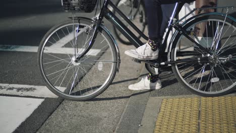 japanese people riding bicycles waiting to cross the road in tokyo, japan