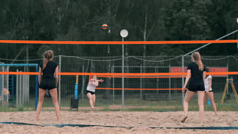 women competing in a professional beach volleyball tournament. a defender attempts to stop a shot during the 2 women international professional beach volleyball.