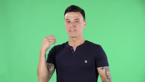 retrato de un joven guapo está esperando algo para pasar y morder su puño. pantalla verde