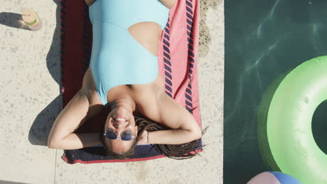 young biracial woman enjoys sunshine by the pool, with copy space