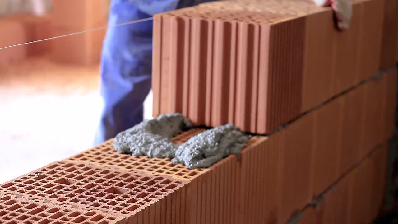 constructores que construyen la pared de ladrillo con los ladrillos rojos metrajes