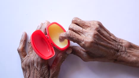 senior woman using petroleum jelly onto skin at home close up