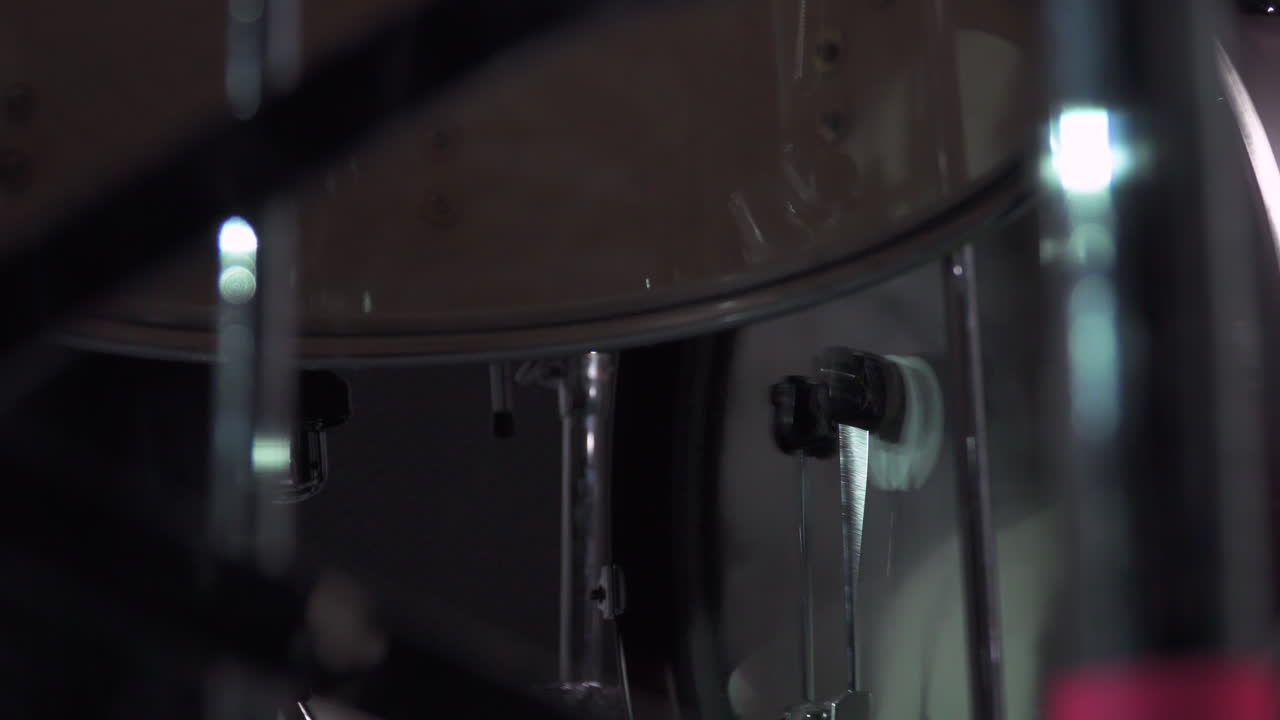 Una scena in primo piano di una doppia cassa di batteria filmata dal basso in un seminterrato buio.