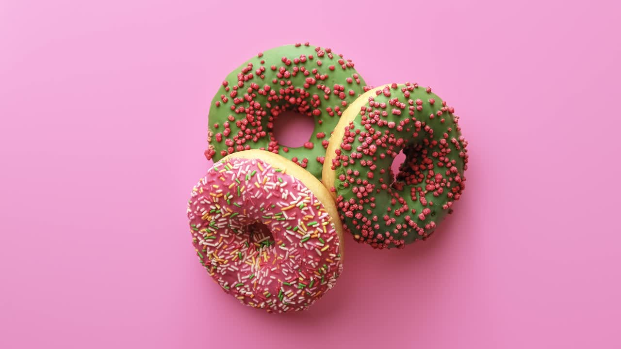 tres anillos de rosquillas girando aislados en fondo rosa. filmado en cámara de cine 4k red raven