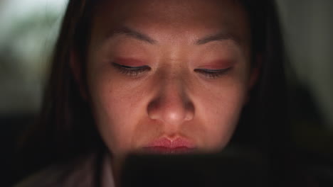 집에서 저녁을 보내고 소파에 누워 휴대전화를 들고 인터넷이나 소셜 미디어를 스크롤하는 여성의 클로즈업 12