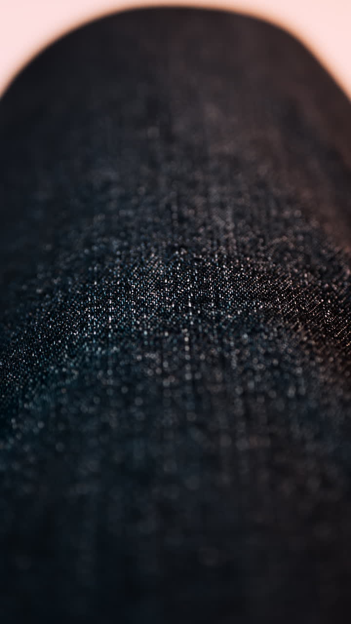 Close up of a dark denim fabric, with small reflective fibers. Vertical