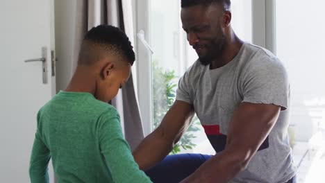 padre afroamericano ayudando a su hijo a vestirse en el dormitorio