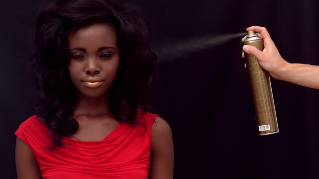 alguien le pone laca para el cabello a una mujer.