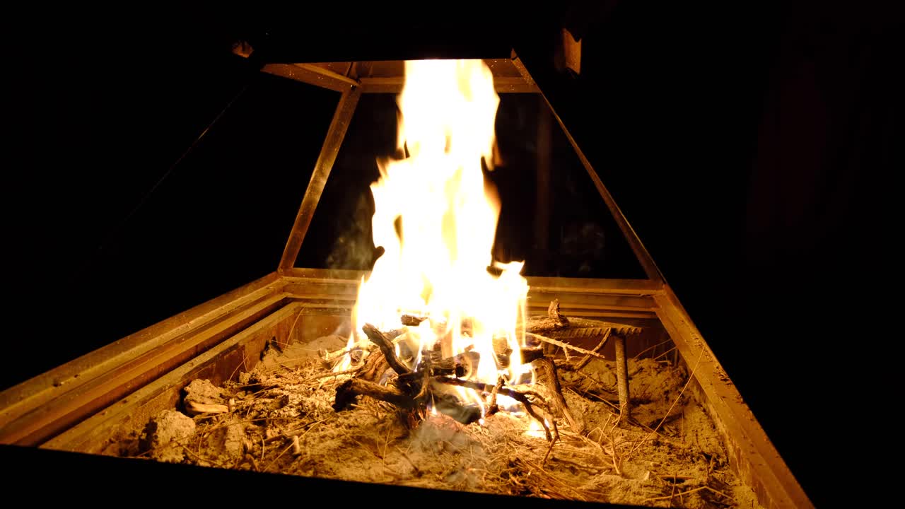 요르단 와디 럼 사막의 황무지에서 야영을 하는 전통적인 아라비아 베두인 텐트 안에서 밤에 타는 장작불을 닫습니다