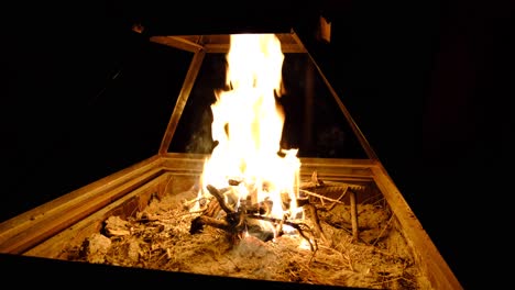 Close-up-of-log-fire-burning-at-night-inside-a-traditional-Arabian-Bedouin-tent,-camping-in-wilderness-of-Wadi-Rum-desert,-Jordan